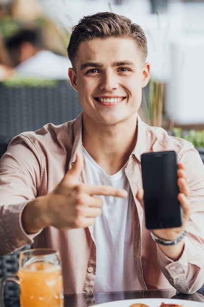 Foto un bellissimo uomo passa il suo tempo con il telefono e la birra