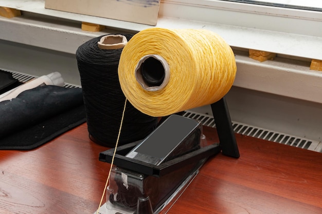 Foto una grande bobina gialla con grandi fili colorati di accoppiamento nello studio per il laboratorio di interior design sul tavolo con filo che si estende verso la telecamera