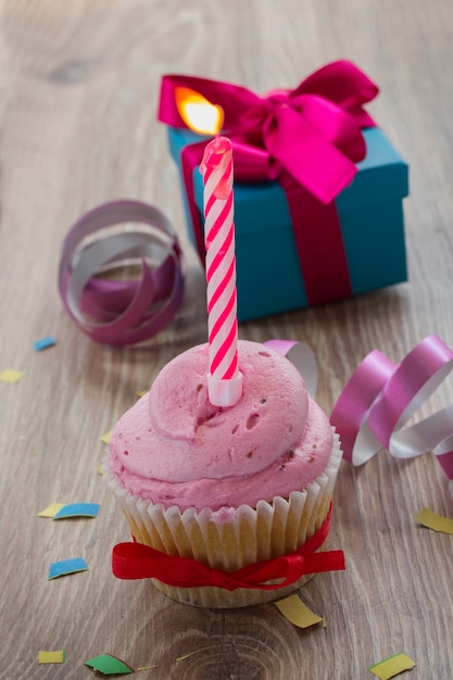 One birthday  cupcake with  burning  candle and gift box