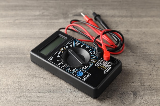 One black multimeter on gray textured background