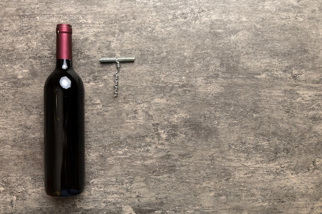 Photo one bottle of red wine with corkscrew on colored table flat lay top view wth copy space