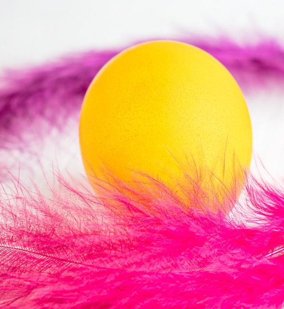 Foto un uovo mangiatore di colore giallo brillante bollito e preparato per la celebrazione decorato con piume rosa