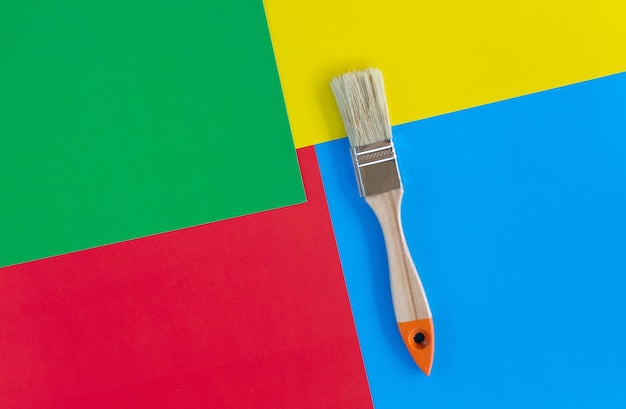 Photo one brush for painting the walls of an apartment or house. brush on background multicolored paper. concept of renovating of apartment, arts and art therapy.