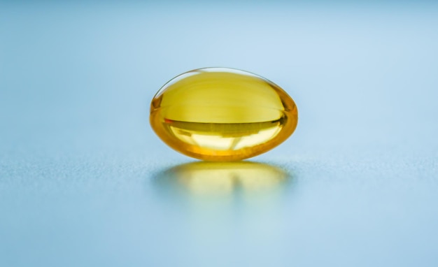 One capsule of fish oil on a blue background