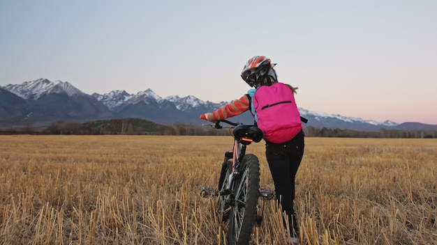 One caucasian children walk with bike in wheat field Girl walking black orange cycle