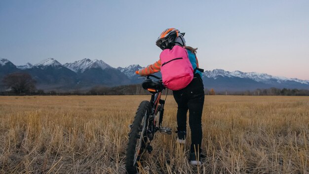 One caucasian children walk with bike in wheat field Little girl walking black orange cycle