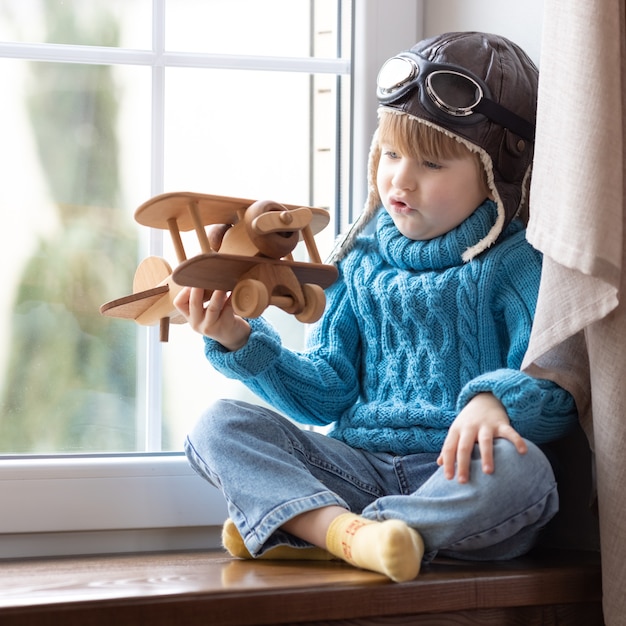 屋内でヴィンテージの木製飛行機で遊んでいる一人の子供