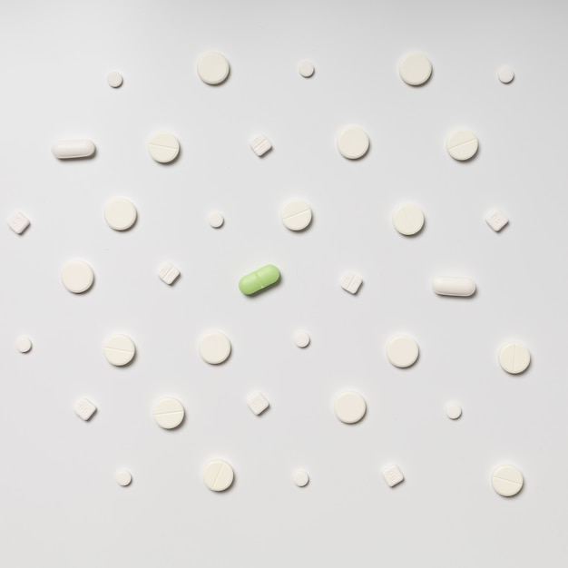 One colored pill on a background of white pills