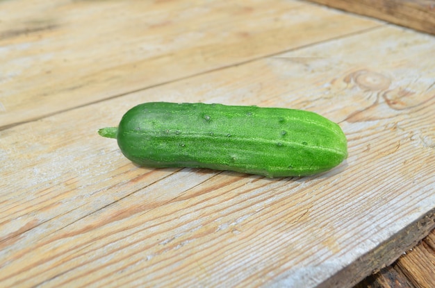 Photo one cucumber on the wooden table ripe cucumber on green background