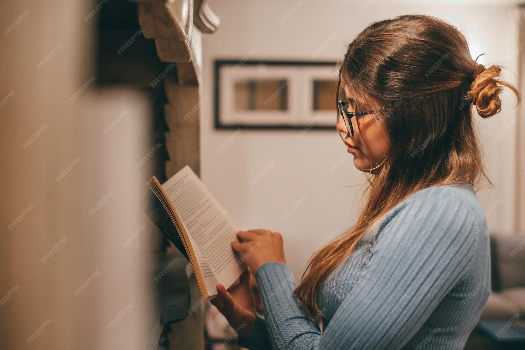 Premium Photo | One cute and attractive wearing eye glasses reading and  looking an interesting book at home indoor young woman relaxing alone at  night reading books