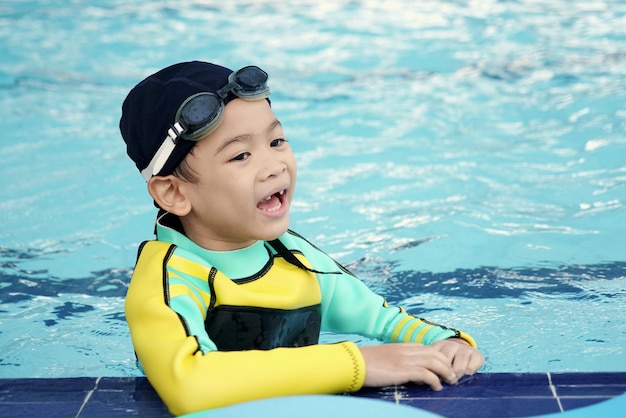 Foto un ragazzo asiatico di smiley sveglio impara la lezione di nuoto nello stagno all'aperto nel tempo di attività.