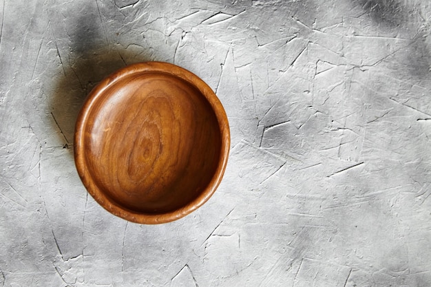 Фото Одна пустая деревянная миска на сером фоне одна круглая миска для салата на каменном столе с видом сверху