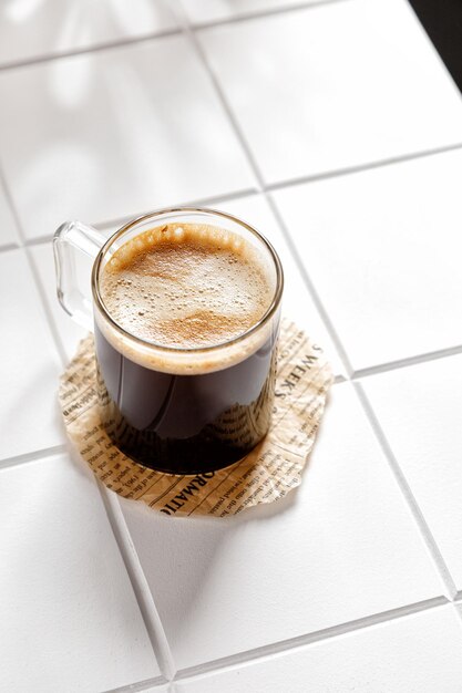 타일이 있는 흰색 배경에 유리 머그에 있는 에스프레소 커피 한 잔