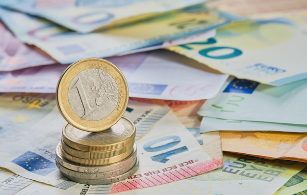 One euro coin on the edge on a stack of coins against the background of banknotes the currency of the European Union Business finance concept business news splash screen banner mockup