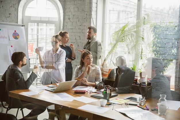 One family. Group of young business professionals having a meeting. Diverse group of coworkers discuss new decisions, plans, results, strategy. Creativity, workplace, business, finance, teamwork.