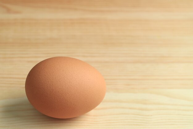 One fresh uncooked hen egg isolated on the wooden table