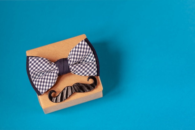 Photo one gift box wrapped in craft paper and tied with the bow tie on blue .