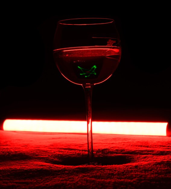 赤いバックライト付きの暗い背景にアルコール カクテルを 1 杯。非常に危険なカクテル。