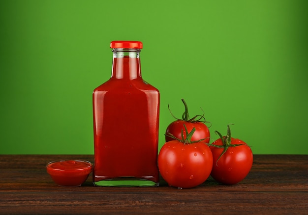 Foto una bottiglia di vetro di salsa ketchup e pomodori rossi freschi sul tavolo di legno wooden