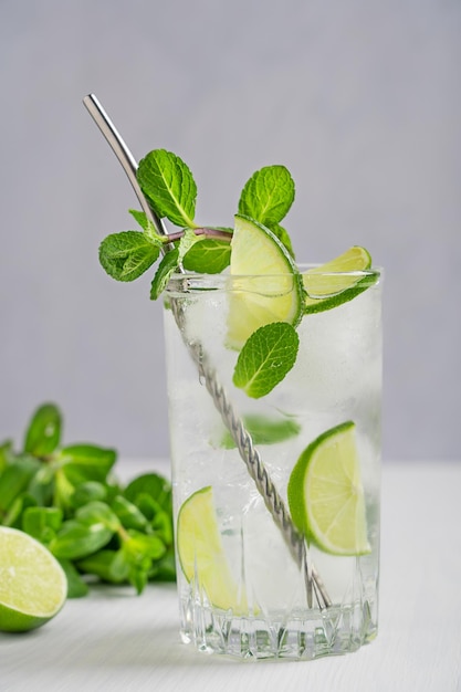 One glass of fresh cold lemonade or mojito drink decorated with lime slices and fresh mint leaves