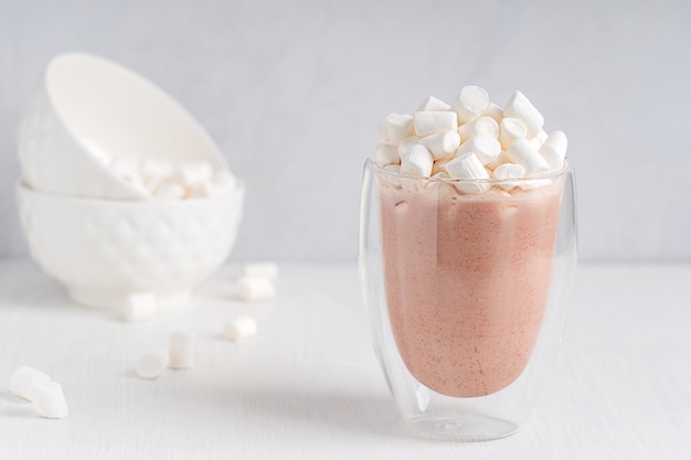 Foto una tazza di cioccolato caldo dolce fatto in casa o bevanda al cacao con marshmallow in cima al tavolo bianco