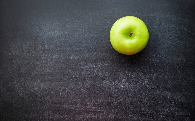 One green apple on a blackboard