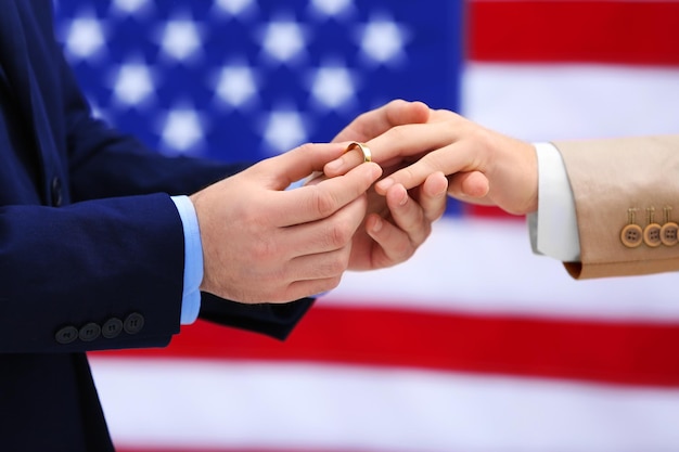 Фото Один жених надевает кольцо на палец другого мужчины на фоне американского флага