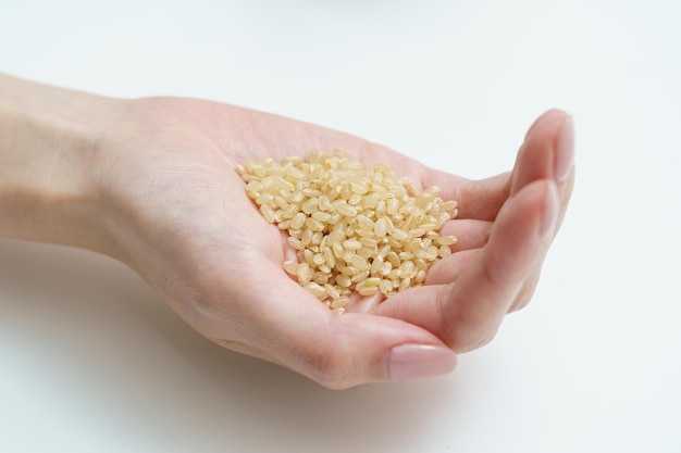 One hand of a woman holding brown rice