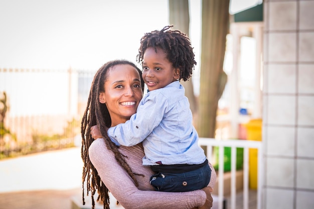 One happy black athnic family afro american mother and son hug together outside home in outdoor leisure activity Mommy and little goy having fun with love and friendship