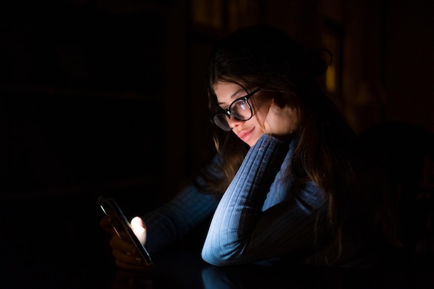 Una donna felice e insonne che usa il telefono a tarda notte nella camera da letto a casa in chat ragazza online che naviga in rete rivedendo il concetto di tecnologia dei social media utilizzando internet