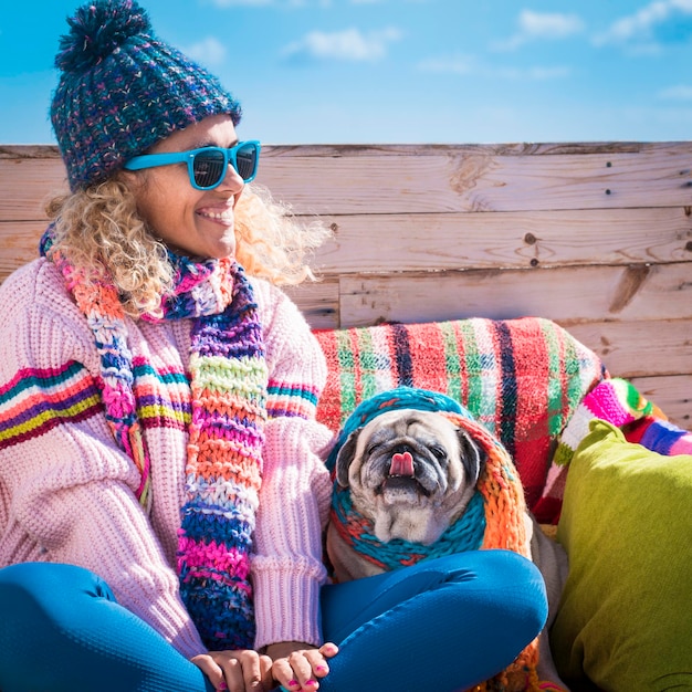 One happy woman smiling with her best friend companion dog pug\
sitting near her winter outdoor leisure activity with people in\
friendship with animals concept of life together with puppy