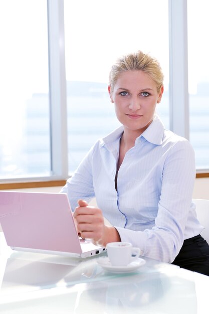 Una felice giovane donna d'affari che lavora su un computer portatile alla riunione del team di gruppo in un ufficio moderno