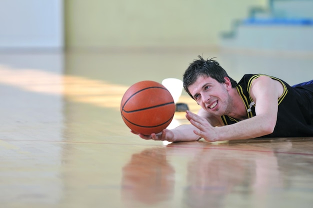 한 명의 건강한 젊은이가 학교 체육관에서 농구 경기를 치르고 있습니다.