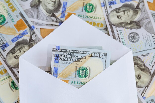 One hundred dollar bills in an envelope lie on a background of dollars. Buying a house or car, corruption.