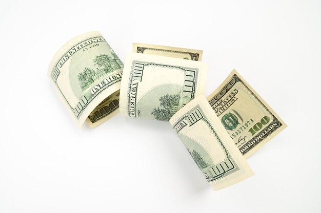 One hundred dollar bills rolled up, on an isolated white background . High quality photo