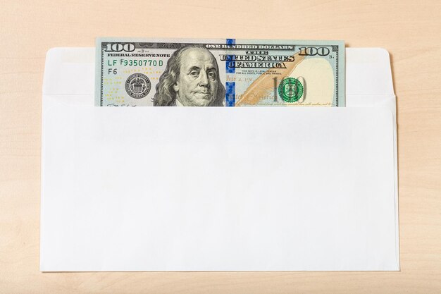 Photo one hundred dollars bill in open envelope on table