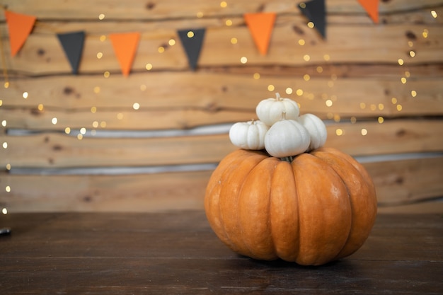 One large orange pumpkin and several small white baby pumpkins on it. Festive halloween background. copy space.