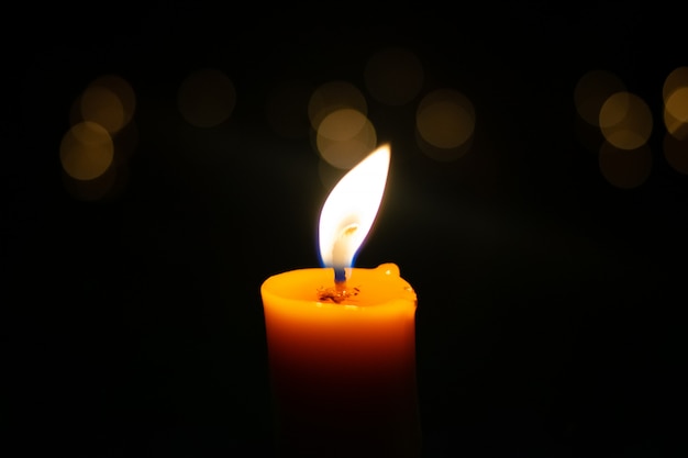 Photo one light candle burning brightly in the black background