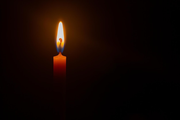 One light candle burning brightly in the black background