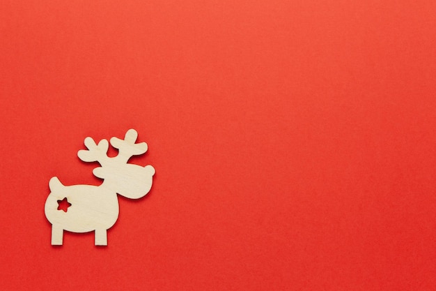 Photo one little wooden deer on bright red background copy space festive new year eco friendly concept