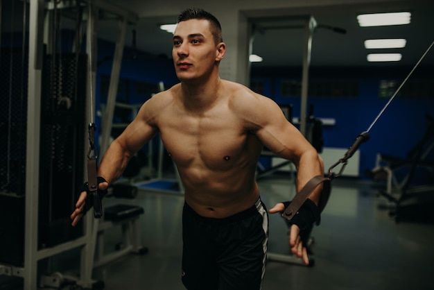 One man exercising suspension training trx in dark gym