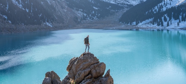 사진 산 호수 위의 유리한 지점에 있는 바위에 서 있는 한 남자