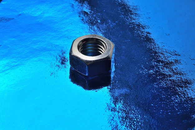 One metal nut lies on an abstract blue background. close-up.