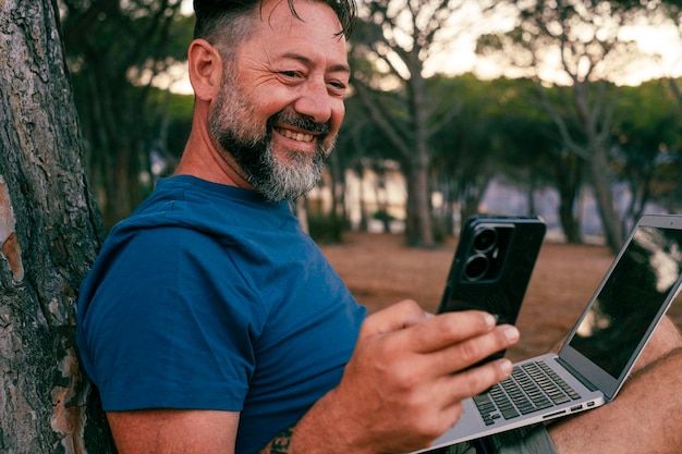 One modern adult man using and working on laptop at the park Concept of smart working and freelance digital nomad small business online free lifestyle People with computer outdoor leisure activity