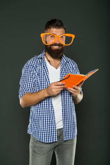 One more chapter University male student reading lecture notes Study nerd holding book Book nerd wearing fancy glasses Bearded man in party glasses with lesson book