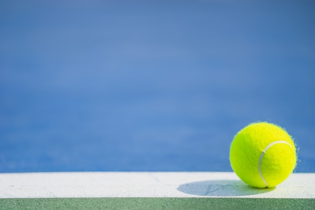 Una nuova palla da tennis su linea bianca in campo duro blu e verde