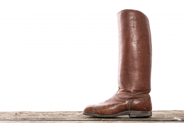 One old leather handmade high boot on wooden floor isolated on white background