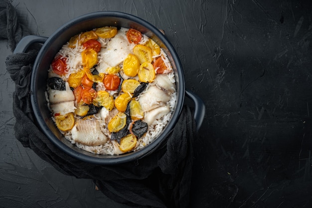 One pan fabulous fish, with basmati rice and cherry tomatoes, on black table, top view