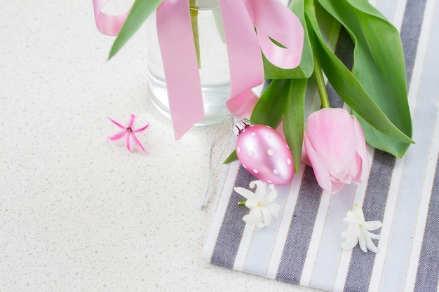 One pastel pink easter egg with fresh tulip with copy space on white table