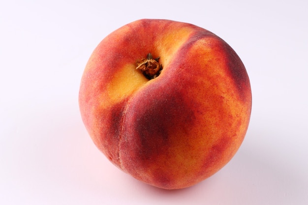 One peach on a white surface close up